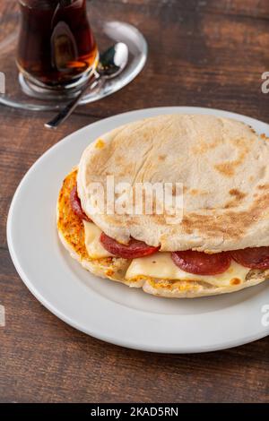 Pain grillé avec salami, saucisse turque et cheddar sur une table en pierre sombre Banque D'Images