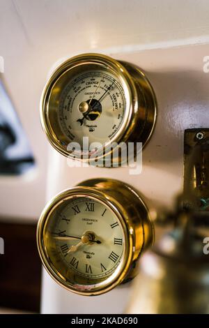 Ancienne horloge dorée et instruments nautiques à l'intérieur d'un catamaran Banque D'Images