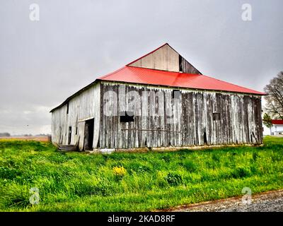 Une ancienne grange rustique en bois sur l'herbe verte avec un toit rouge dans l'Indiana Banque D'Images