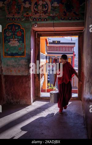 Un jeune moine traversant une porte au monastère de Thiksey, Ladakh, Inde Banque D'Images