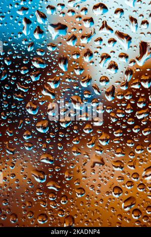 Gros plan vertical de grosses gouttes de pluie sur le verre Banque D'Images
