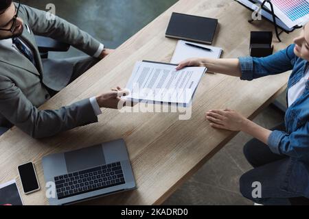 Vue de dessus du gestionnaire et du CV de mise en attente du candidat à proximité des périphériques du bureau, image de stock Banque D'Images