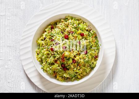 choux de bruxelles à la crache aux amandes, bacon croquant et canneberges dans un bol blanc sur une table en bois, vue verticale depuis le dessus, plat, gros plan Banque D'Images