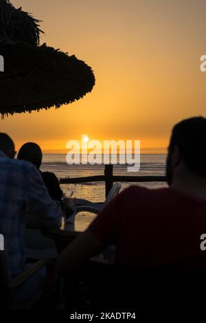 Peu de personnes appréciant leur soirée avec une vue sur l'océan au coucher du soleil Banque D'Images