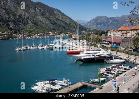 Kotor, Monténégro - 29 avril 2022 : Voiliers, bateaux à moteur et petits bateaux de pêche amarrés à la jetée de la baie de Kotor. Montagnes en arrière-plan. Banque D'Images