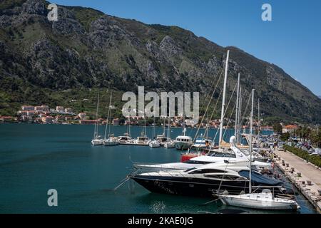 Kotor, Monténégro - 29 avril 2022 : Voiliers, bateaux à moteur et petits bateaux de pêche amarrés à la jetée de la baie de Kotor. Montagnes en arrière-plan. Banque D'Images