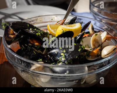 Un grand bol en verre de moules, palourdes et crevettes (fruits de mer, frutti di mare) décoré de citron, sur une table de restaurant au Monténégro, en Europe. Banque D'Images