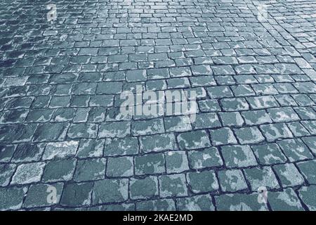 Vue de dessus sur le pavage de la route de la pierre humide après la pluie. Vieux pavés de granit de texture. Cobblestone rue trottoir. Résumé fond pour la conception. Banque D'Images