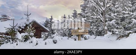 joyeux noël écrit sur une affiche en bois à côté d'un chalet alpin et d'une forêt dans la neige Banque D'Images