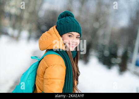 Profil vue latérale portrait d'une fille gaie attrayante portant une tenue chaude allant à l'école collège neige temps dehors Banque D'Images