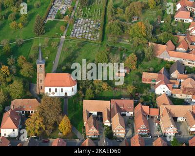 VUE AÉRIENNE. Église protestante surplombant la rue principale avec ses maisons à colombages uniques. Hunspach, Bas-Rhin, Alsace, Grand est, France. Banque D'Images