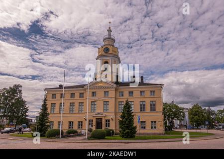 Finlande, Hamina - 18 juillet 2022: Face arrière de la ville en pierre jaune ou de l'hôtel de ville, Haminan raatihuone, avec tour d'horloge sous le paysage de nuages gris de thcik. Vert Banque D'Images