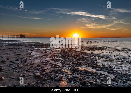 Baigneurs dans la mer à la plage de Penarth au lever du soleil un matin d'été. Banque D'Images