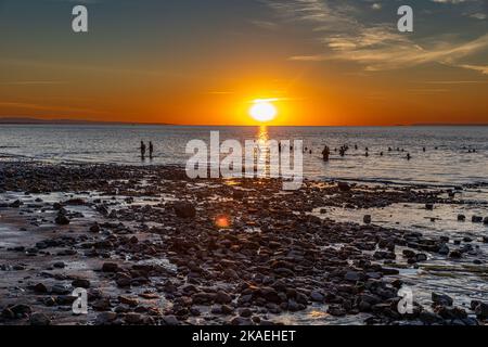 Baigneurs dans la mer à la plage de Penarth au lever du soleil un matin d'été. Banque D'Images