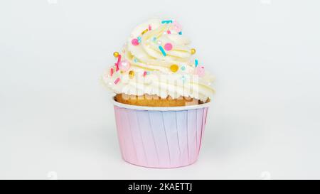 Muffin à la vanille dans un gobelet en papier dégradé rose sur fond gris clair. Cupcake à la crème de beurre et aux asperges dorées en gros plan. Gâteries et desserts pour Banque D'Images