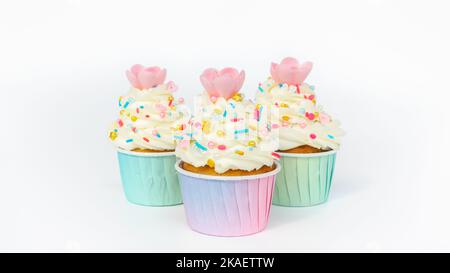 De magnifiques petits gâteaux aux arrosettes dorées sur une crème au beurre en gros plan. Muffins à la vanille dans des tasses en papier dégradé sur fond blanc avec espace de copie. Delici Banque D'Images