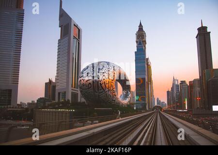 Dubaï, Émirats Arabes Unis - 10th octobre 2022 : métro sur chemin de fer à Dubaï avec musée du futur et ciel de coucher de soleil Banque D'Images