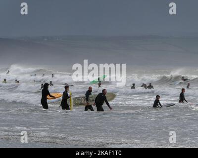 Les surfeurs pénètrent dans la mer dans des conditions difficiles lors d'une journée venteuse à Saunton Sands, dans le Devon, en Angleterre Banque D'Images