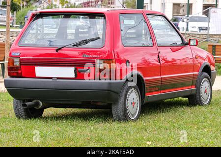 Une voiture de sport rouge Fiat Uno Turbo c'est-à-dire debout sur l'herbe verte Banque D'Images