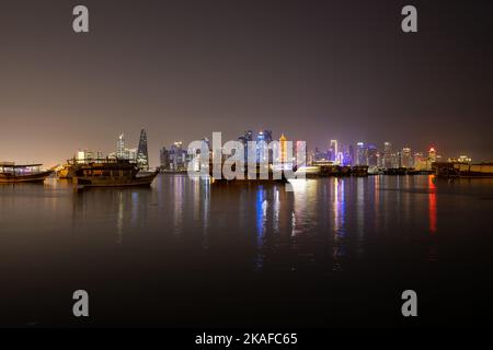 Le port de Doha, Qatar la nuit avec ses gratte-ciel et ses vieux bateaux traditionnels Banque D'Images