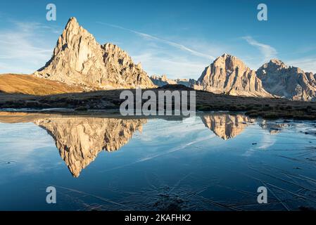 Les montagnes de Ra Gusela et Tofane di Rozes se reflètent dans l'eau et la glace d'un lac lors d'une matinée d'automne glacielle à Passo di Giau, Dolomites, Italie Banque D'Images