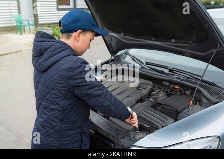 Mécanicien de voitures pour enfants dans la rue pour réparer une voiture. La vue de l'arrière. Réparation de voiture Banque D'Images