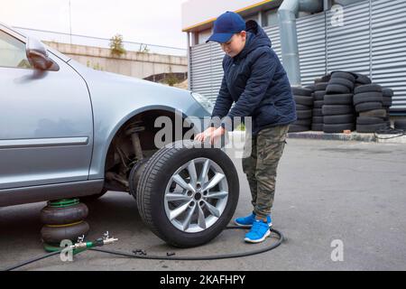 Mécanicien homme changer un pneu de roue et entretien de la suspension d'un véhicule , contrôle de sécurité moteur avant le client conduire une voiture sur un Banque D'Images