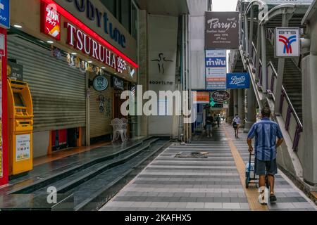 Un liveur pousse un chariot de camion à main le long de la rue Silom, à côté de la gare BTS de Saladaeng à Bangkok, en Thaïlande. Banque D'Images