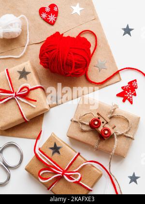 Cadeaux de Noël et du nouvel an dans du papier artisanal. Cadeaux de Noël liés avec des fils blancs et rouges avec jouet train et coeur rouge symbole comme décoration. Banque D'Images