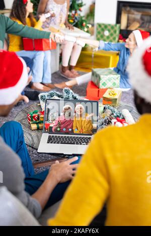 Divers amis avec des décorations de noël ayant des appels vidéo avec heureux divers couple Banque D'Images