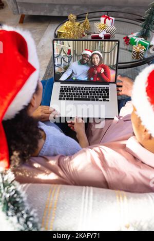 Couple biracial avec décorations de noël ayant appel vidéo avec heureux couple divers Banque D'Images