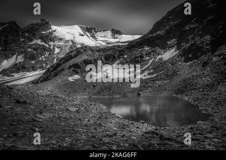 Vue en noir et blanc du petit lac glaciaire vert parmi les moraines Banque D'Images