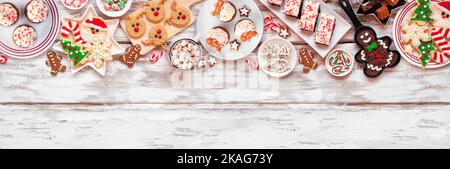 Bonbons de Noël mignons et bordure supérieure de biscuit. Vue ci-dessus sur un arrière-plan rustique de bannière en bois blanc avec espace de copie. Concept de pâtisserie amusant pour les vacances. Banque D'Images