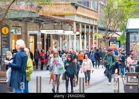 Les gens qui marchent et regardent ou lisent leurs téléphones mobiles lorsqu'ils se déplacent dans le centre commercial Pitt Street Mall, dans le quartier commercial de Sydney, en Australie Banque D'Images