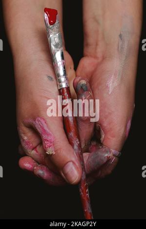 gros plan des mains d'un artiste avec une brosse en couleur Banque D'Images