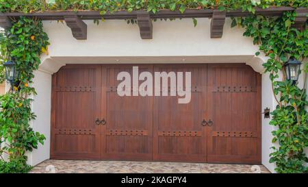 Panorama portes de garage doubles à charnières latérales en bois sombre à la Jolla, Californie. Extérieur d'un garage avec plantes rampantes sur la pergola attachée et un dr Banque D'Images