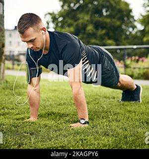 Poussez-vous un peu plus loin à chaque fois. Un jeune homme sportif s'exerçant à l'extérieur. Banque D'Images