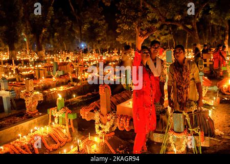 Nadia, Inde. 02nd novembre 2022. Les gens prennent des selfies dans un cimetière pendant la journée de tous les Souls. Les dévotés chrétiens se rassemblent aux tombes de leurs proches dans un cimetière avec des bougies et des fleurs illuminées pendant la journée des All Souls' Day. Un jour où les chrétiens se souviennent de leurs amis et de leurs proches, qui sont morts. Cela vient d'une croyance ancienne que les âmes des morts reviendront, ce jour-là, pour avoir un repas avec leur famille et leurs amis. Des bougies sont allumées pour guider les âmes vers leur maison pour le repas. Crédit : SOPA Images Limited/Alamy Live News Banque D'Images