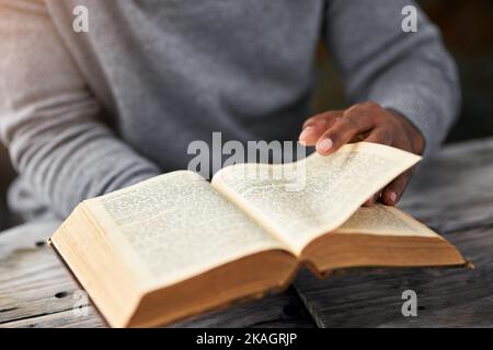 Il est temps de tourner la page. Photo en grand angle d'un homme méconnaissable lisant sa bible tout en étant assis à l'extérieur. Banque D'Images