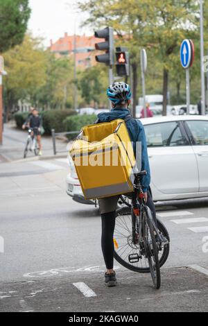 Cycliste livraison de nourriture homme attendant avec un feu de circulation de vélo à traverser à Madrid. Concepts de durabilité et d'écologie Banque D'Images
