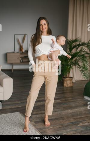 Belle jeune mère tient son petit fils heureux dans ses bras et ressemble mignon ensemble comme une famille qui s'aime l'un l'autre Banque D'Images