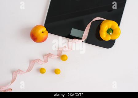 Pêche biologique et poivre et ruban de mesure pour peser les balances avec un régime de légumes végétaliens. Régime alimentaire et mode de vie sain. Design fin et fin. Banque D'Images