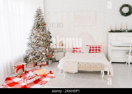 Spacieuse chambre lumineuse de style loft aux couleurs blanche et rouge avec un sapin de Noël décoré Banque D'Images