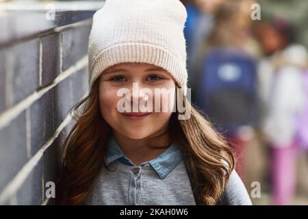 Souriant jusqu'à sa prochaine classe, une fille de l'école primaire dans le couloir de l'école. Banque D'Images