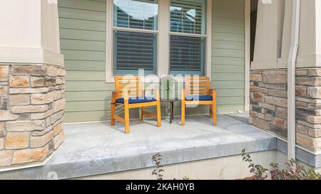 Panorama deux petite chaise en bois avec assise et plantes en pot sur la table au milieu. Porche avant d'une maison avec plantes et chaises longues n Banque D'Images