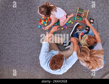 Famille, enfants et apprendre avec des jouets éducatifs, blocs et abacus pour le jeu de couleur avec maman et papa sur le sol. Homme et femmes parents avec enfants pour Banque D'Images