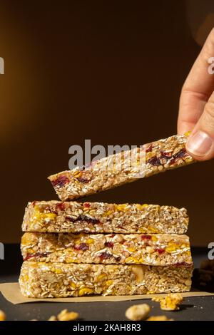 Femme prend le bar énergétique Granola naturel maison. Variété de barres de petit-déjeuner de granola de protéines, avec noix, raisins secs, cerises séchées et chocolat. Nutrition saine alimentation. Collation sans gluten aux céréales Super food Sport Oridge bar Vega dessert concept Banque D'Images