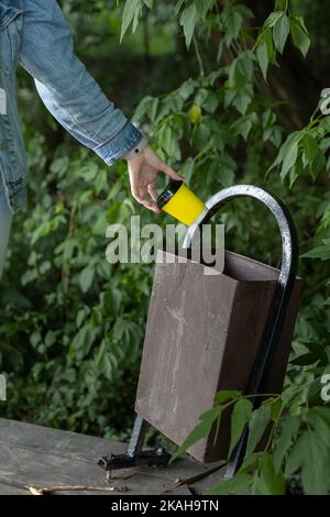 un homme jette une tasse de papier dans l'urne. la main jette le verre. vieille poubelle. poubelle cassée Banque D'Images