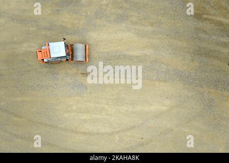 Vue verticale d'un rouleau de compacteur de sol isolé , machine de construction travaillant sur un chantier. Préparation de la base pour la fondation du parc Banque D'Images