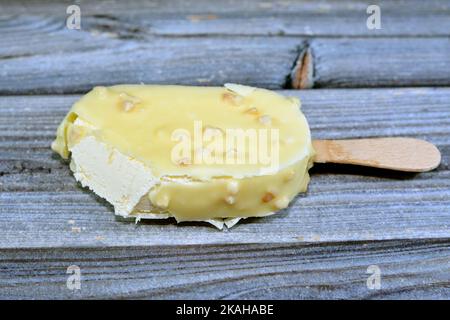 Bâton de glace à la vanille enrobé et recouvert d'une couche de chocolat blanc avec des noix, glace riche aromatisée à la vanille en chocolat blanc craquant et Banque D'Images